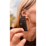 Person using a hoop earring size guide to measure an earring against their ear.