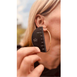 Person using a hoop earring size guide to measure an earring against their ear.