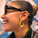 Woman wearing gold hoop earrings with a blurred colorful background